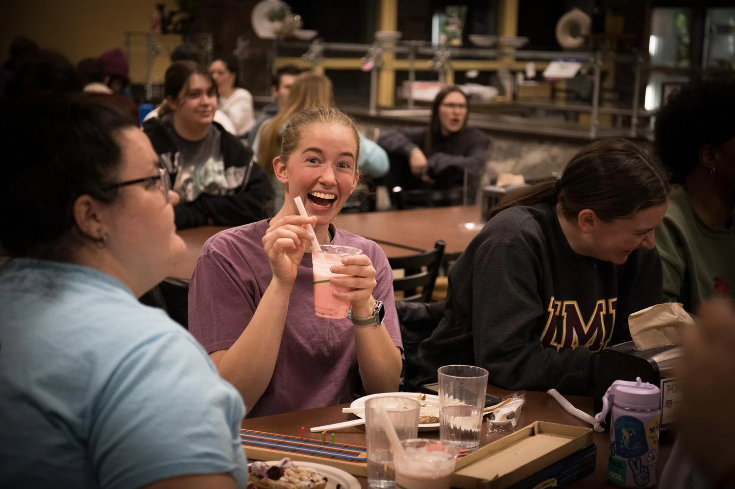 Students smiles at camera holding a smoothie.