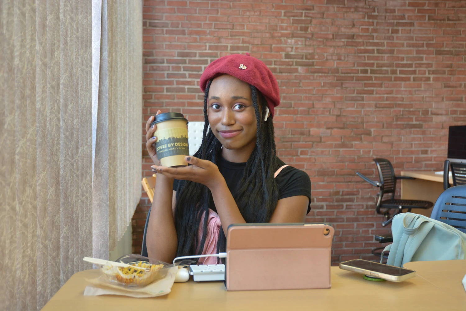 Farmington student holds up a cup of coffee and smiles.