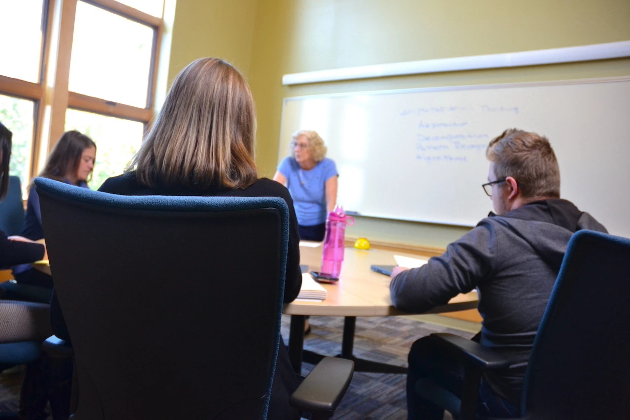 five people sitting around a table listening and paying attention to each other.