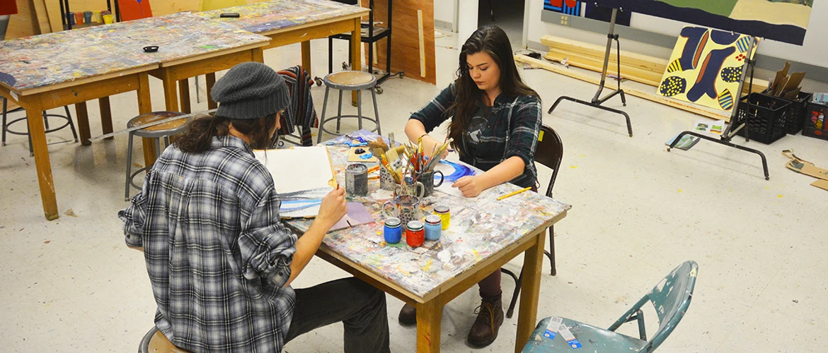 Two students painting within the UMF paint studio
