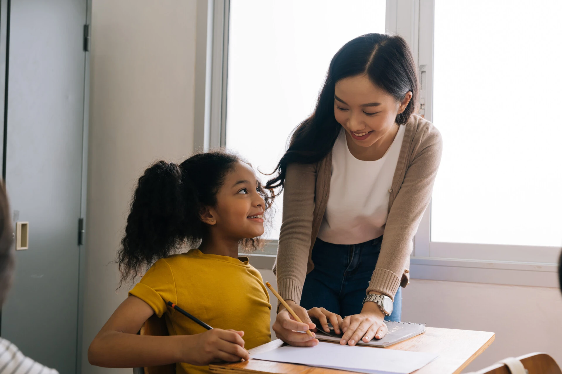 Female student teacher helping a young student with an assignment