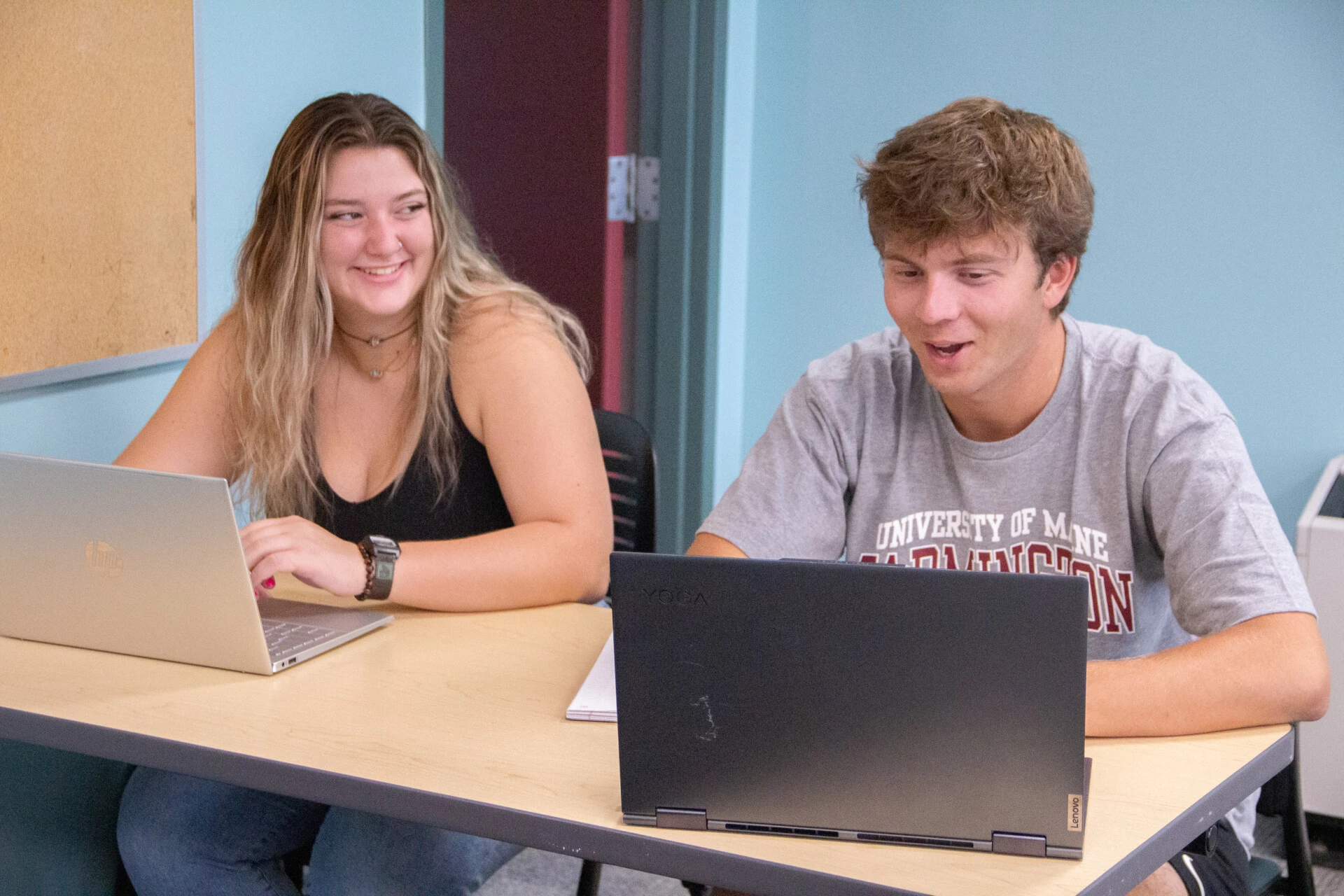 Female and Male students talking while using their latops
