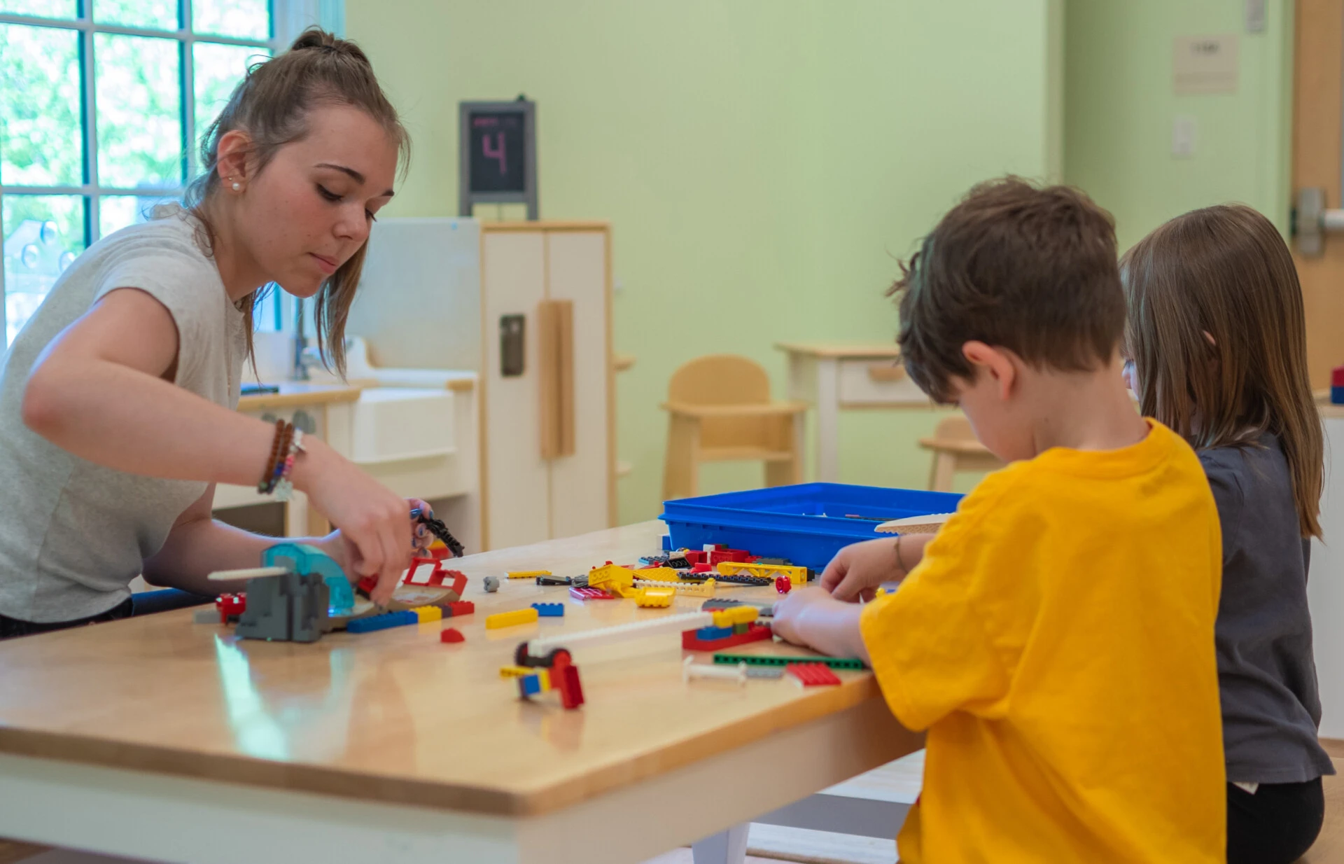Female student working to build legos with two children