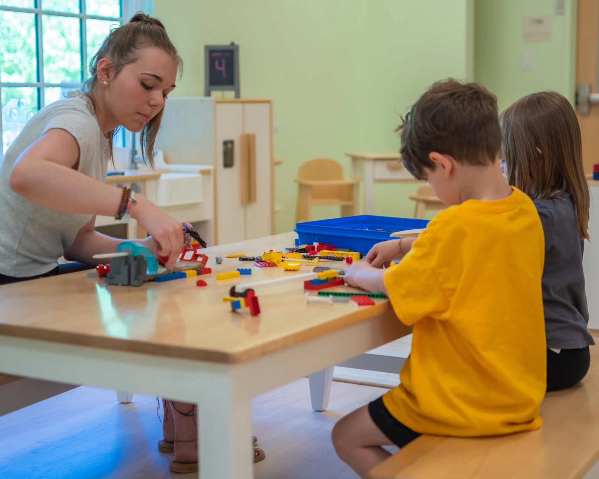 Female student working to build legos with two children