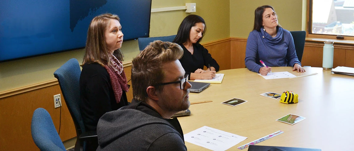 Students sit around a large table.