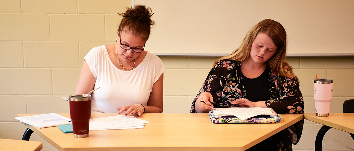 Graduate UMF students sit at a table working on paper.
