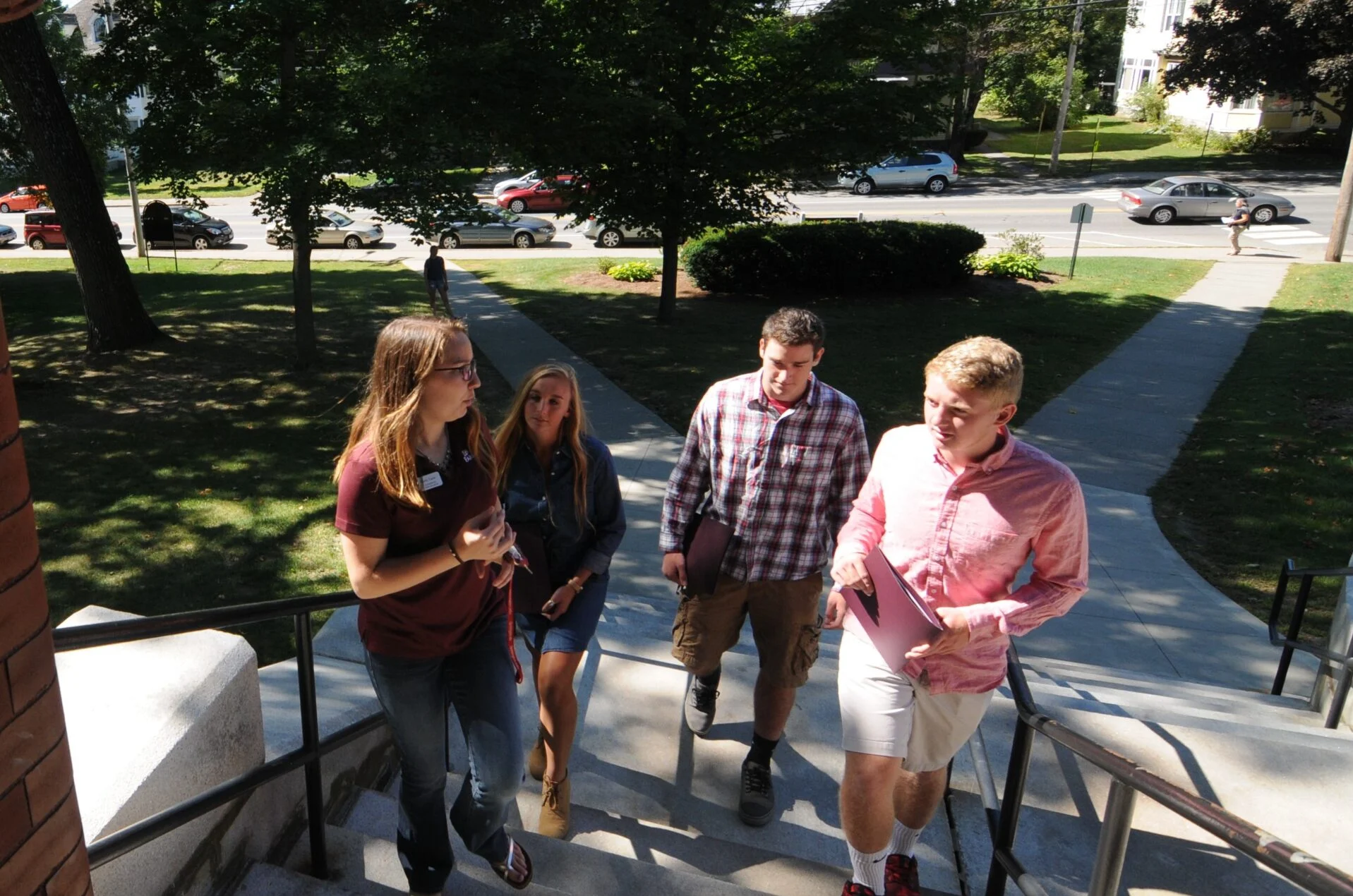 People on a campus tour standing on steps in the front of a building