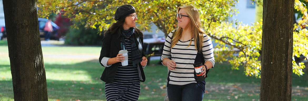 Two people walking in a park chatting with coffee in hands