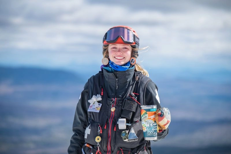 Outdoor Recreation Business Administration major Leah is dressed in snow gear, holding a cup and smiling.