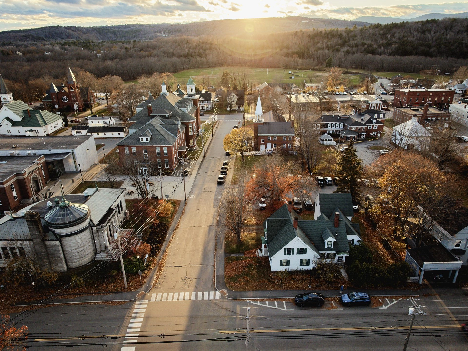 Aerial image of University of Maine Farmington Campus with sun setting over the mountains in the distance.