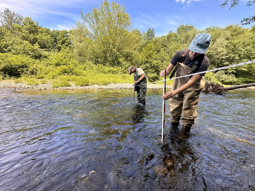 UMF students measure stream flow near a river restoration site.