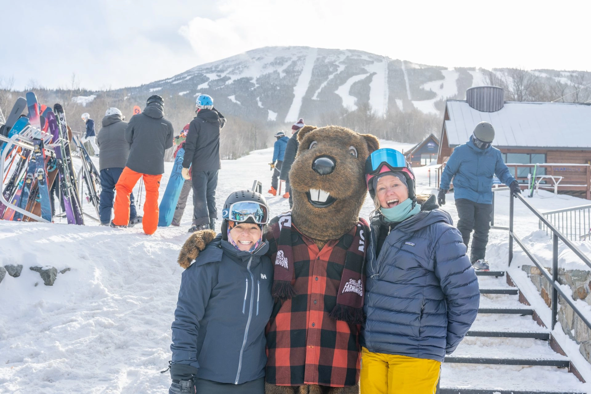 Chompers mascot standing on ski mountain with two students