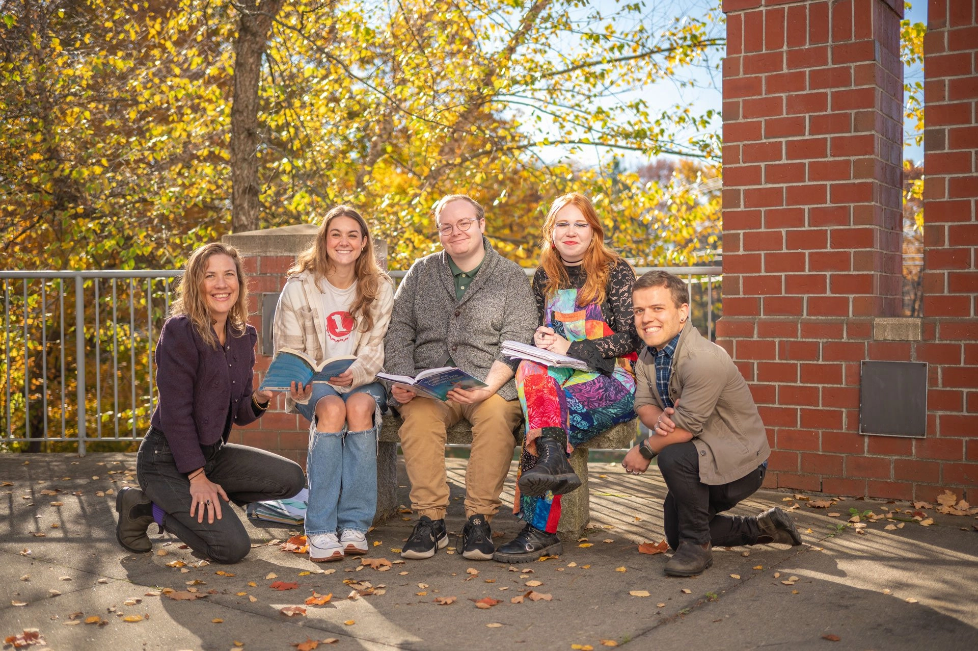 Students sitting together on a bench outside holding books