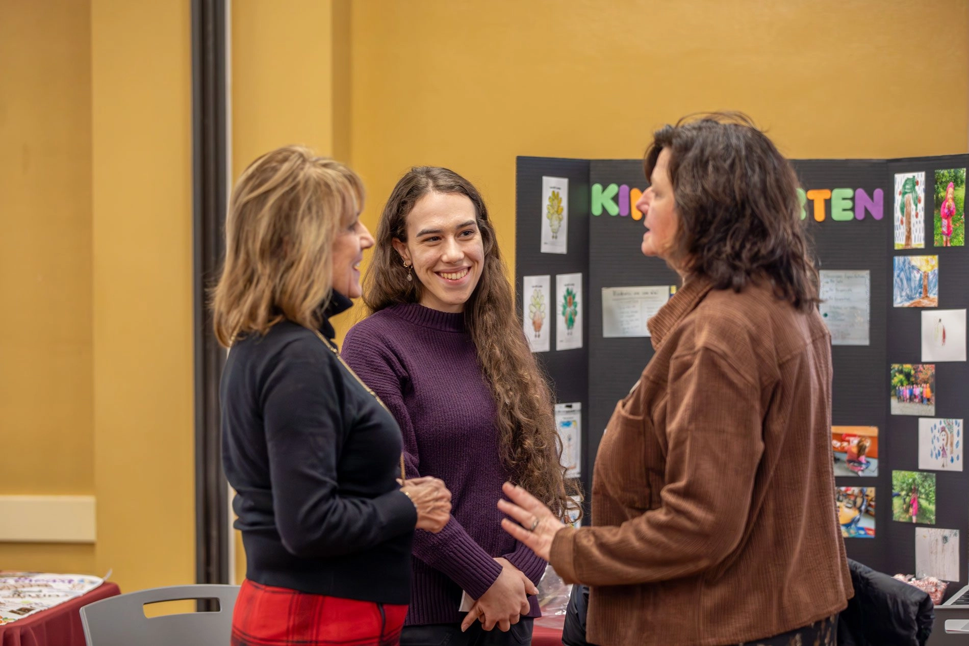 Student in front of display chatting with two mentors