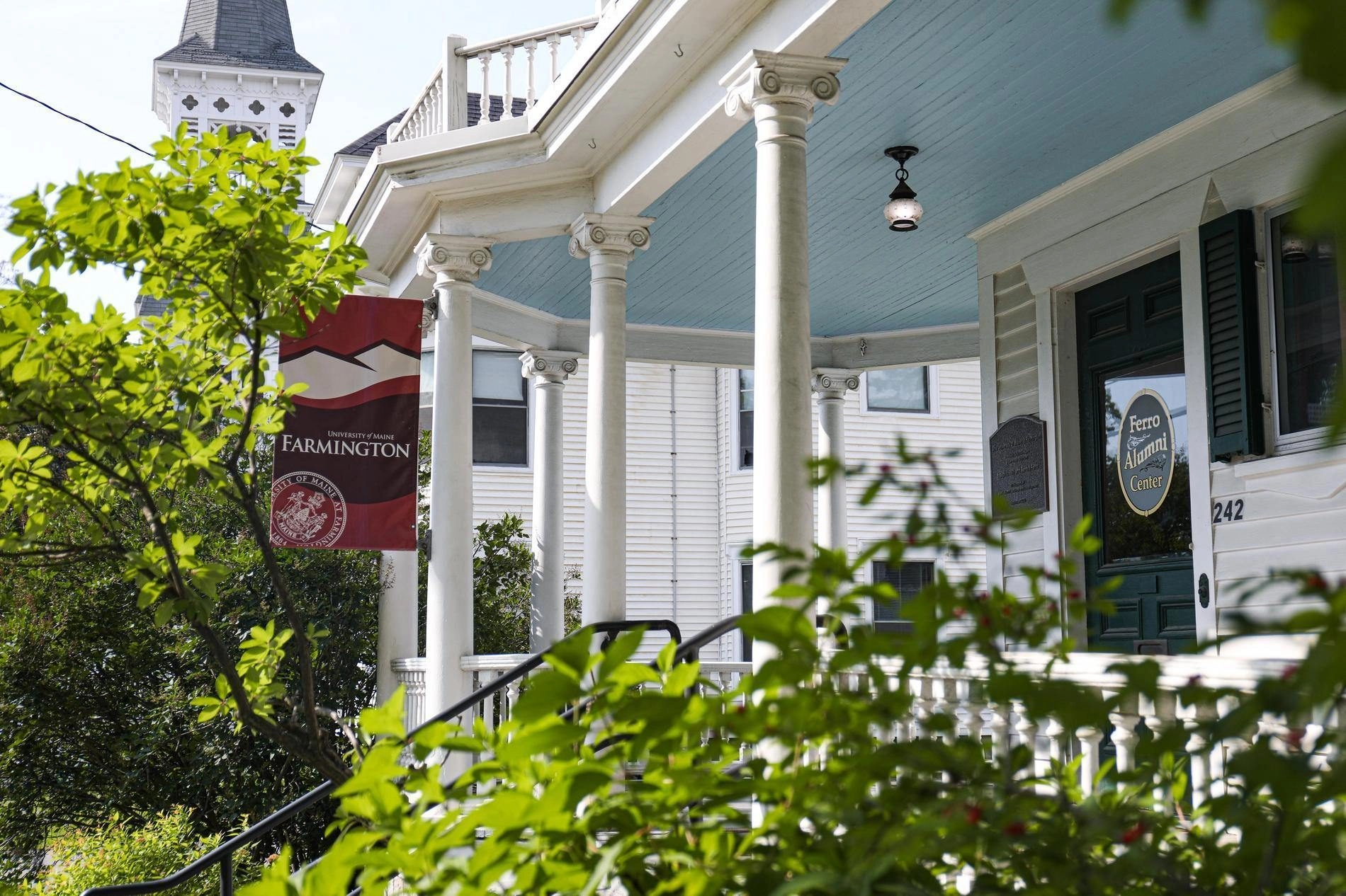 Front porch and door of Ferro Alumni Center with greenery and banner