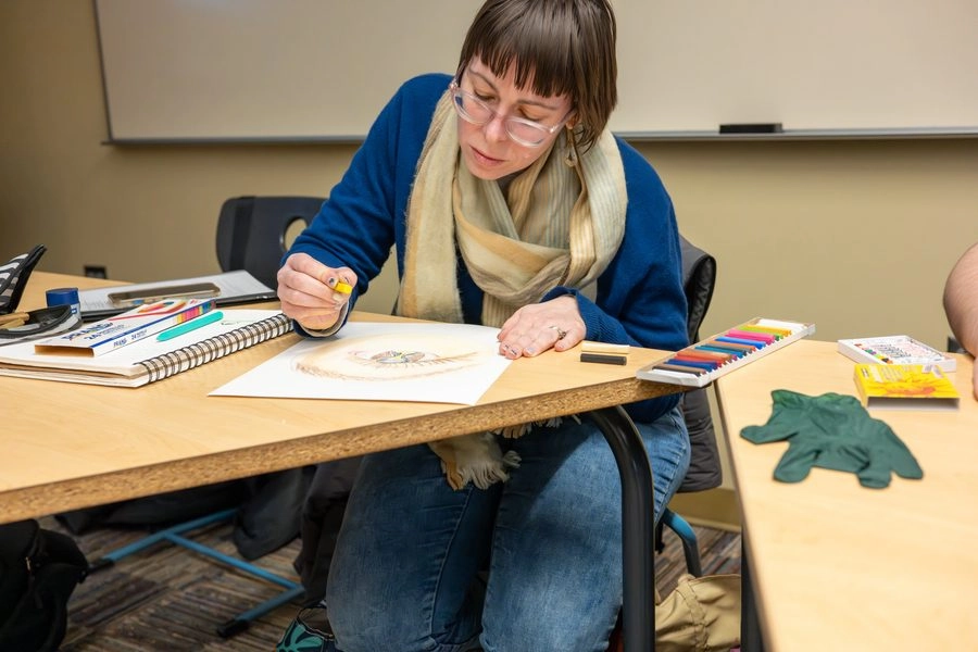 Student working at a desk with art supplies