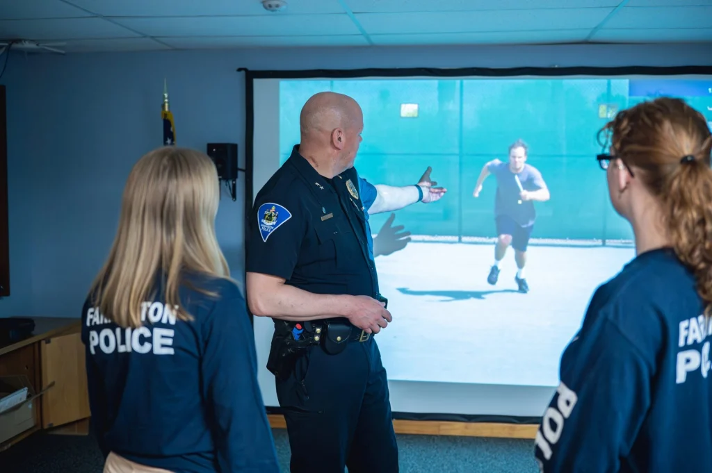 Farmington Police Chief Charles shows student interns the interactive use of force simulator.