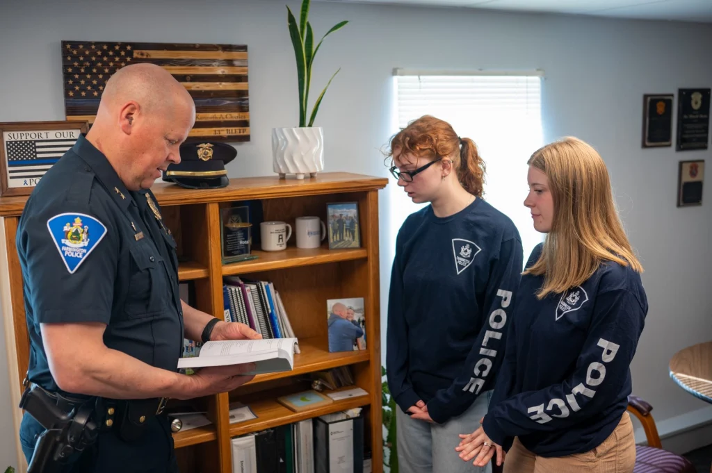 Chief Charles and UMF interns Sydney Booth and Grace White review Maine statutes.