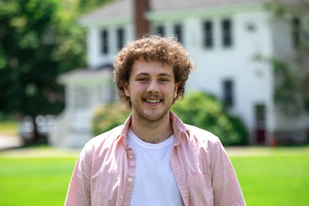 Smiling student standing on the UMF campus green on a sunny day