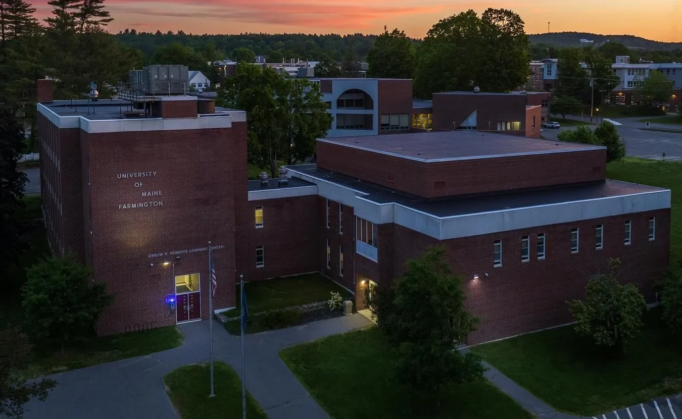 Aerial view of a brick university building at sunset on a green campus (University of Maine at Farmington).