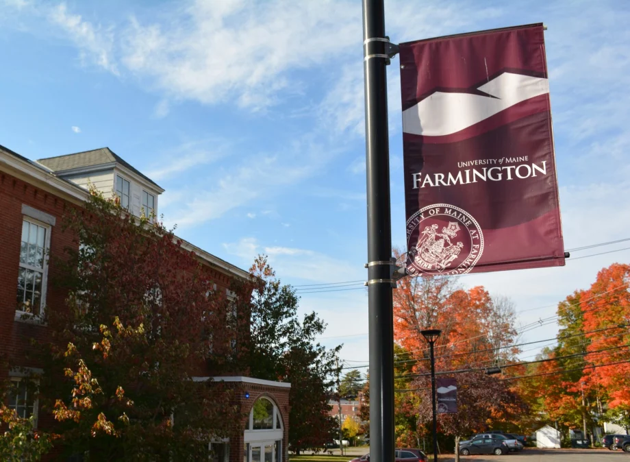 UMF banner outside of Merrill Hall on a beautiful fall day