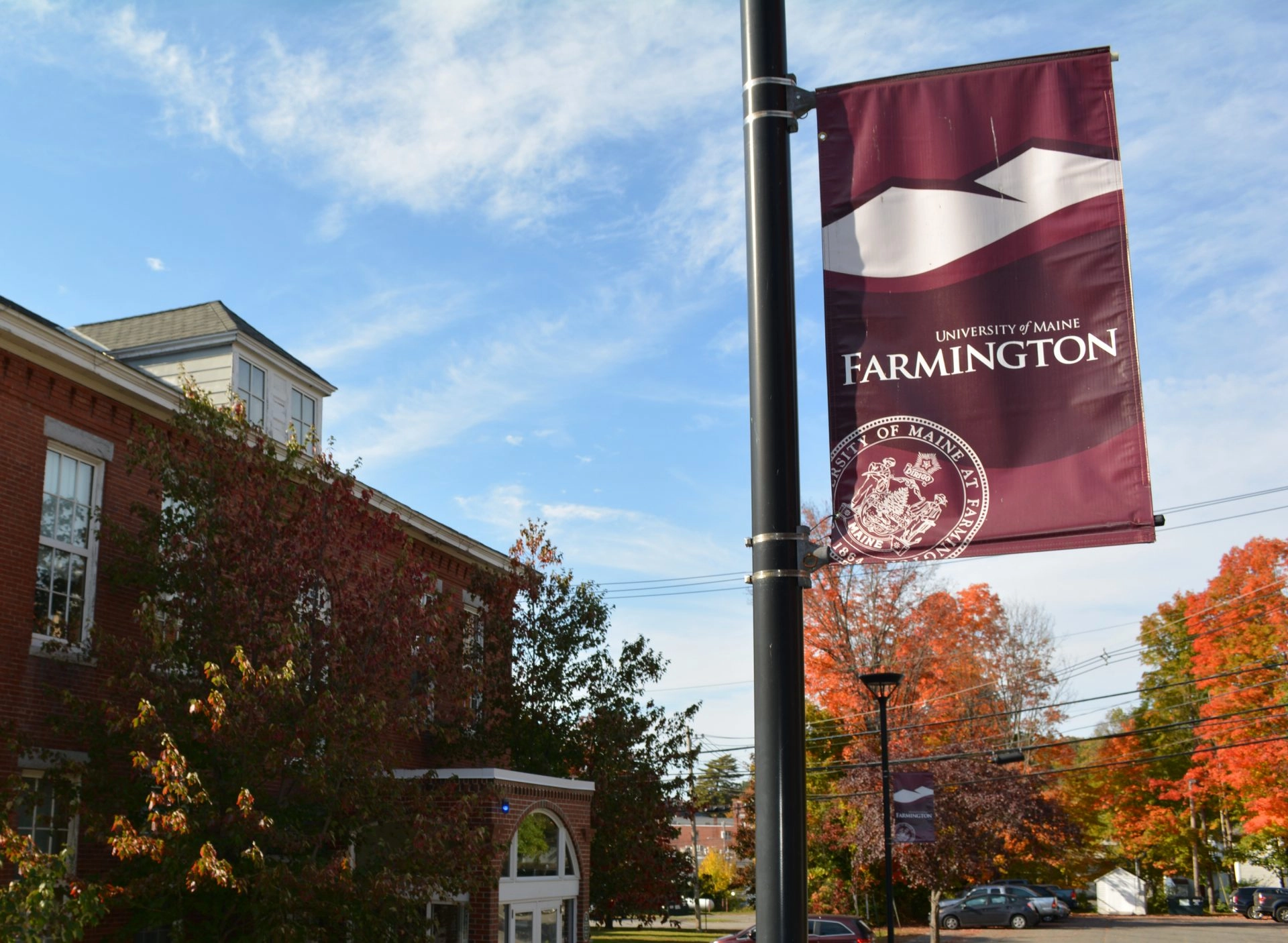 UMF banner outside of Merrill Hall on a beautiful fall day