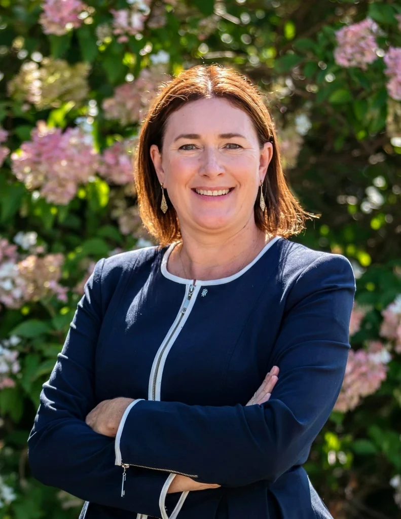 Smiling woman in navy blue suit with arms folded