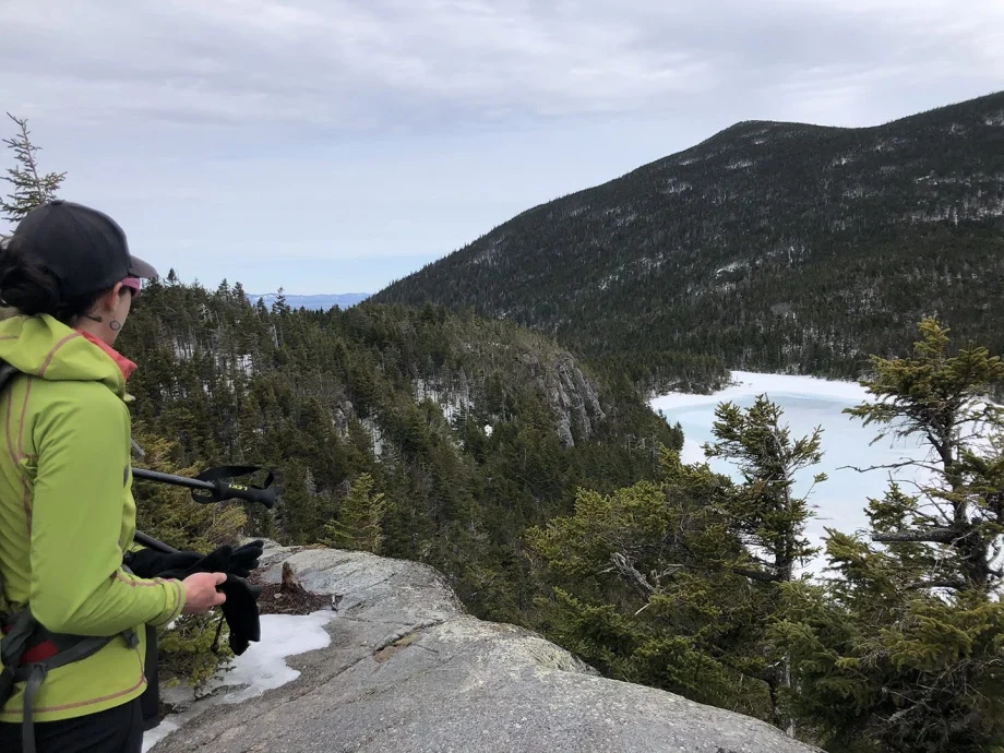 Woman in winter jacket looking out at Maine mountain pond