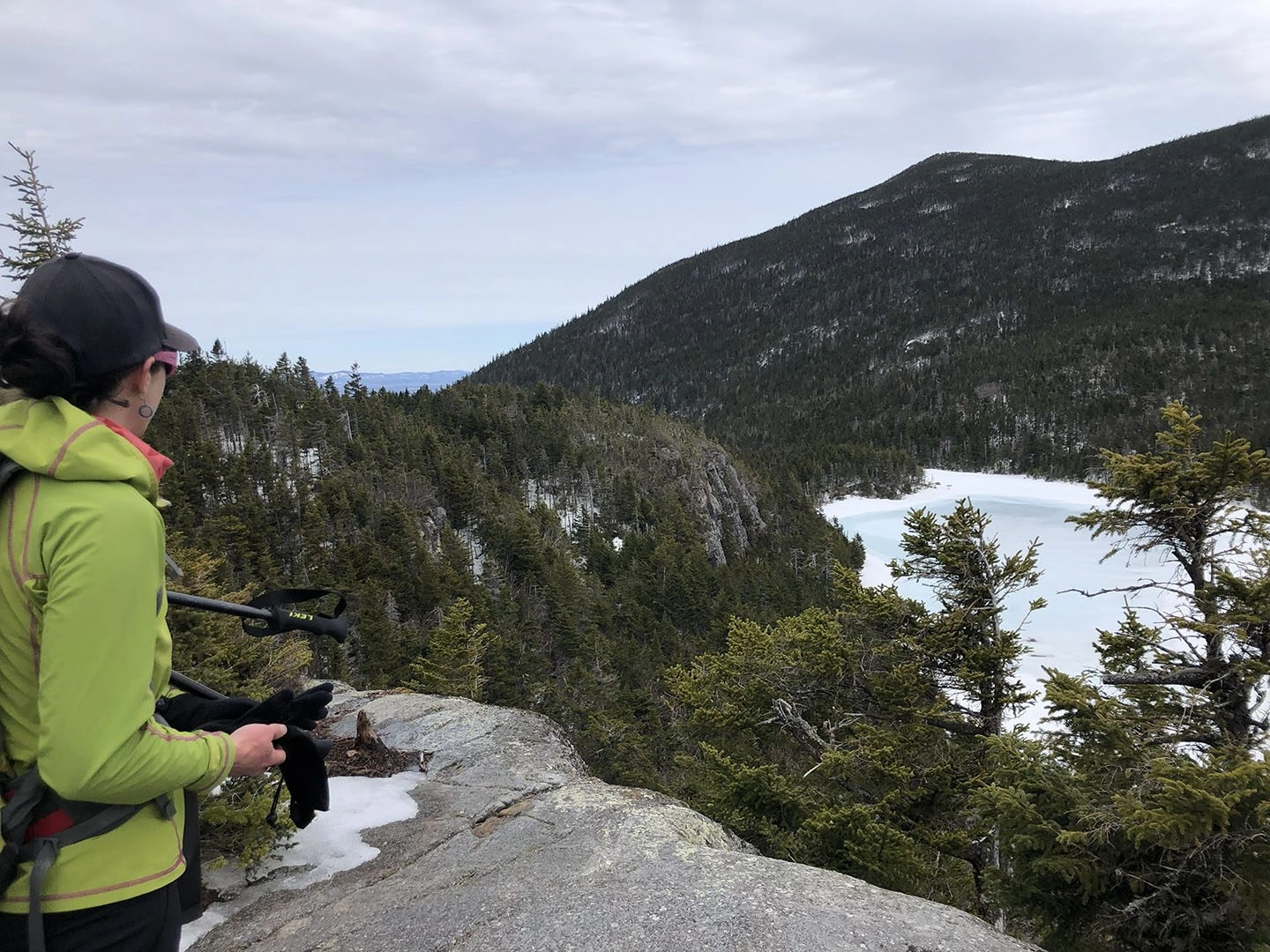 Woman in winter jacket looking out at Maine mountain pond