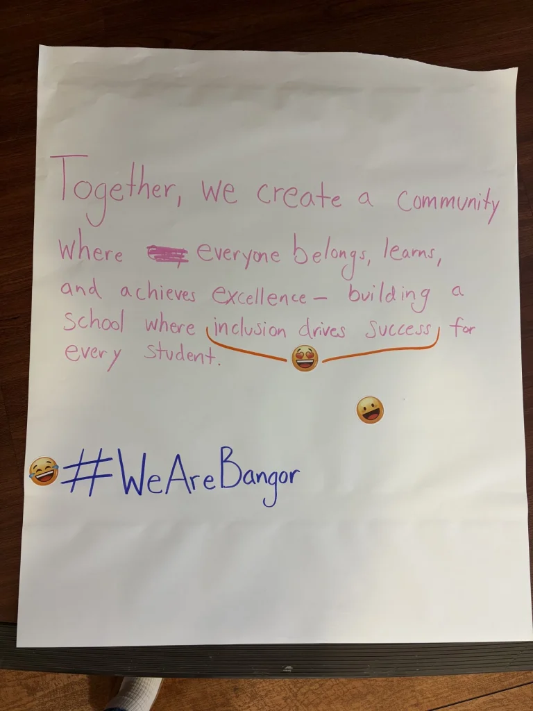 Handwritten pink-ink poster promoting an inclusive school community, with emojis and the hashtag #WeAreBangor.