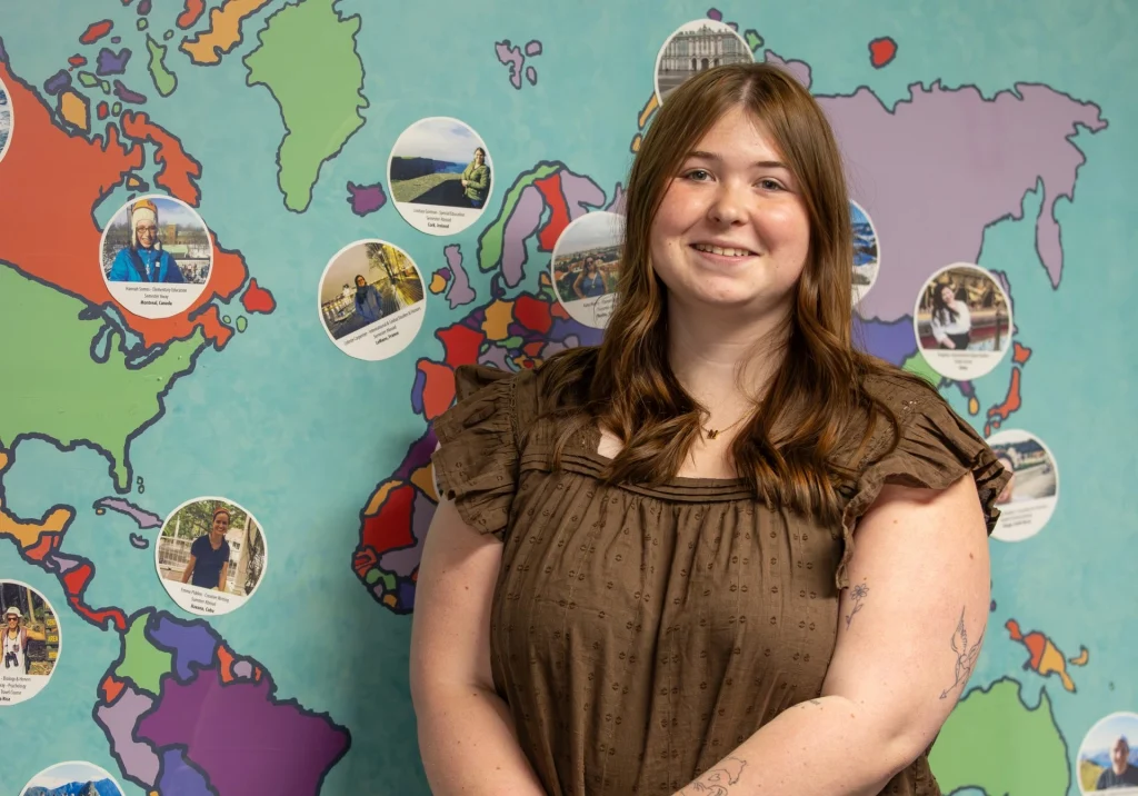 Young woman smiling in front of a map of the world