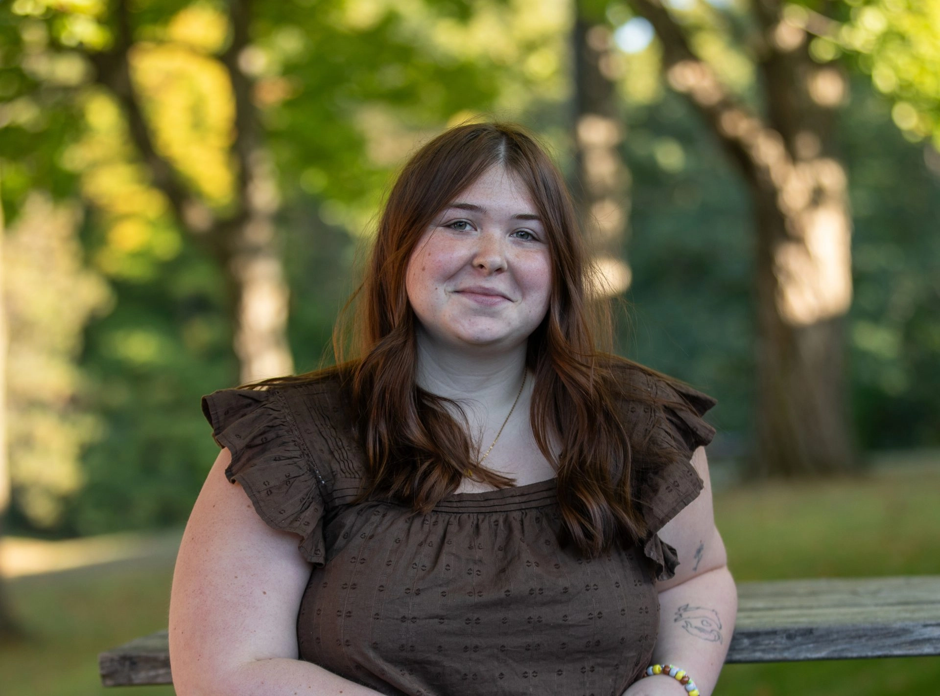 Young woman in a brown blouse seated outside